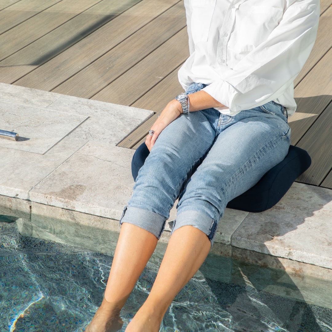 Women sitting on Blue Biggie's Seat Cushion placed the edge of the swimming pool with her feet under the pool