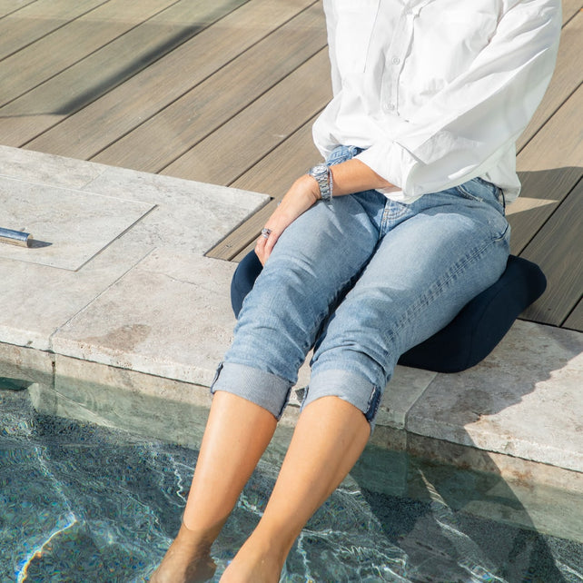 Women sitting on Blue Biggie's Seat Cushion placed the edge of the swimming pool with her feet under the pool